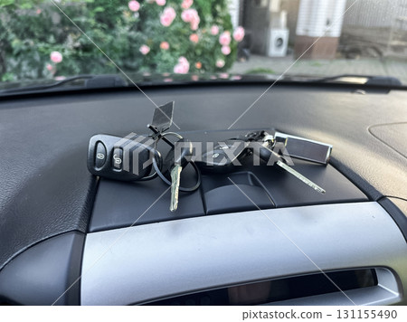 Keys resting on the dashboard near blooming flowers in a sunny setting, capturing a peaceful moment of everyday life 131155490