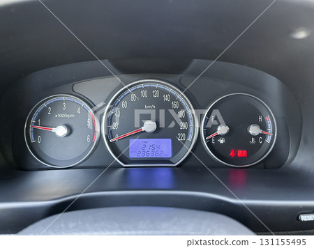 Dashboard of a modern vehicle showing speed, distance, and fuel level during a road trip in daylight 131155495