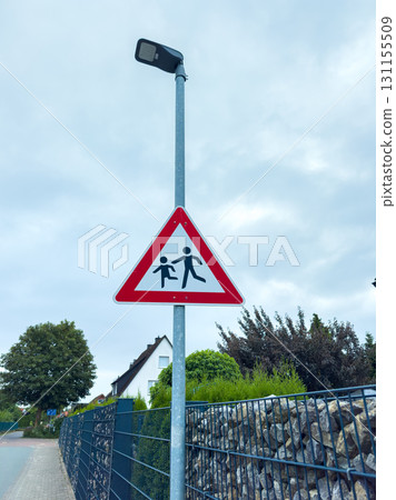 Caution sign marking children's crossing area near residential street on a cloudy day 131155509