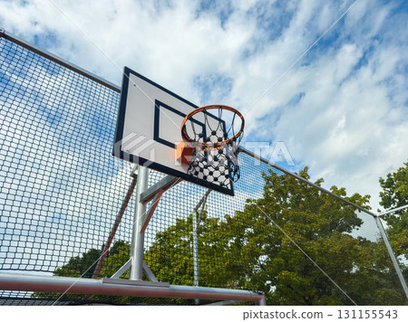 Hoop stands tall under a blue sky at the city basketball court, inviting players to enjoy a game in the afternoon light Hoop stands tall under a blue sky at the city basketball court, inviting players to enjoy a game in the afternoon light 131155543