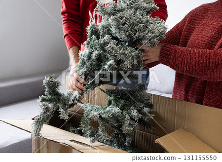 Young couple unpacking Artificial Christmas Tree from Storage Box at home 131155550