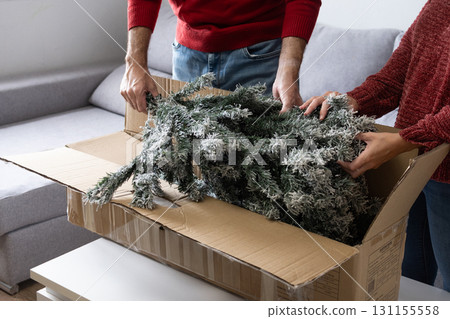 Young couple unpacking Artificial Christmas Tree from Storage Box at home 131155558