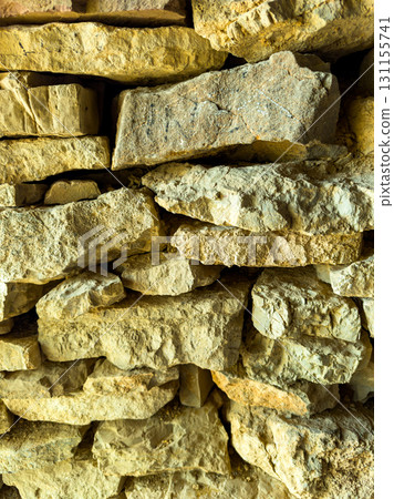 Natural stone wall displaying intricate textures and earthy tones in a warm sunlight setting creating an inviting atmosphere at a rustic location 131155741