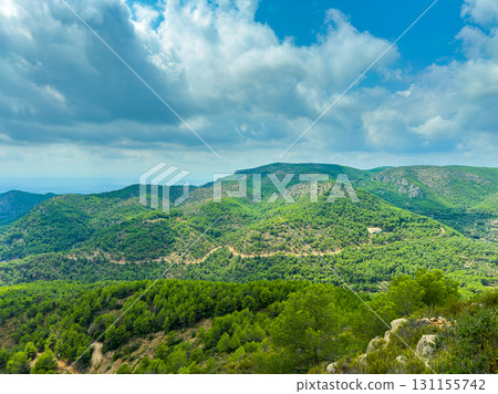 Scenic view of lush green hills under a cloudy sky in a mountainous region during mid-afternoon 131155742