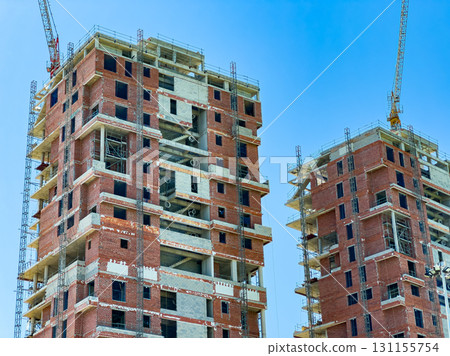 New high-rise buildings take shape under bright blue sky during construction in a busy urban area filled with promise and potential New high-rise buildings take shape under bright blue sky during construction in a busy urban area filled with promise and potential 131155754