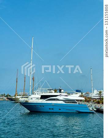 Luxury yacht docked in a marina surrounded by boats and clear blue skies on a sunny day 131155808
