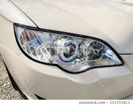 Detail of a car headlight showcasing its design and shine during daylight in an outdoor setting Detail of a car headlight showcasing its design and shine during daylight in an outdoor setting 131155821
