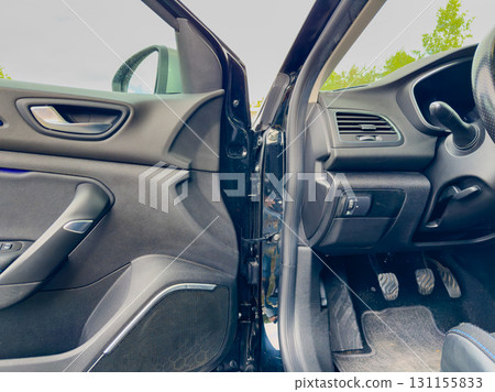 Experience the sleek design and technology inside a modern car parked by a lush green landscape on a cloudy day 131155833