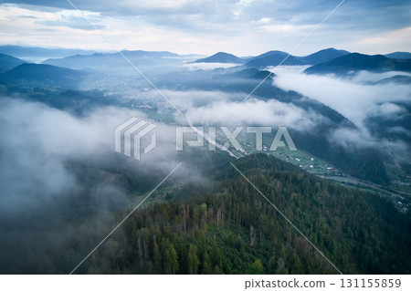 Breathtaking aerial view of valley enveloped in morning mist, with river winding through lush green hills and village nestled among trees. Breathtaking aerial view of valley enveloped in morning mist, with river winding through lush green hills and village nestled among trees. 131155859