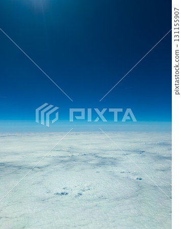 Endless white clouds stretch beneath a bright blue sky during a serene flight above the horizon on a clear day 131155907