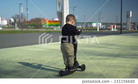 A Happy Child Riding a Bright Scooter in the Open Park, Enjoying an Adventurous Day A Happy Child Riding a Bright Scooter in the Open Park, Enjoying an Adventurous Day 131156680