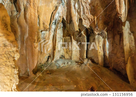 A cave with a brown wall and a brown floor. The cave is dark and has a mysterious atmosphere. 131156956