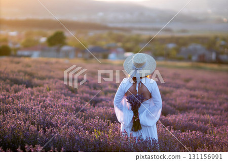 Here's a title following your specifications: Lavender Field Woman Sunset: Harvesting purple lavender blooms at sunset in rural field; picturesque summer scene. Here's a title following your specifications: Lavender Field Woman Sunset: Harvesting purple lavender blooms at sunset in rural field; picturesque summer scene. 131156991