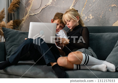 Children Laptop Sofa - Kids using laptop while sitting on a sofa at home. 131157033