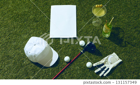 Golf cocktail set with cap glove club and blank copy space paper on grass 131157349