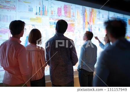 diverse team looking at large wall projection charts diverse team looking at large wall projection charts 131157949