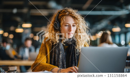 young woman with wireless headphones typing laptop in coworking hub 131158864