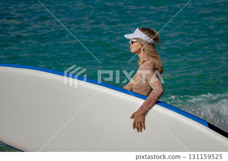 Woman Paddleboard Ocean: Blonde woman carrying board in turquoise water on sunny day for sport. 131159525