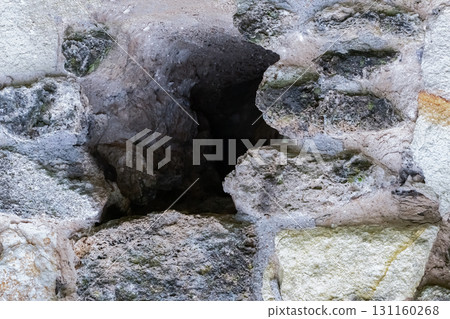 hole in the stone wall of an old house close-up of gray and black stone 131160268