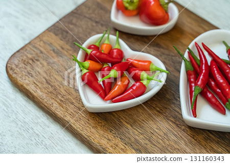 assorted red chili peppers and heart shaped plate set selective focus assorted red chili peppers and heart shaped plate set selective focus 131160343