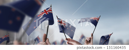 New Zealand flags in their hands on a blurred urban background New Zealand flags in their hands on a blurred urban background 131160435