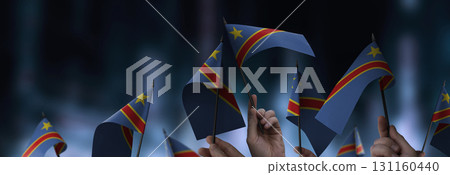 Democratic Republic of the Congo flags in their hands on a blurred urban background Democratic Republic of the Congo flags in their hands on a blurred urban background 131160440