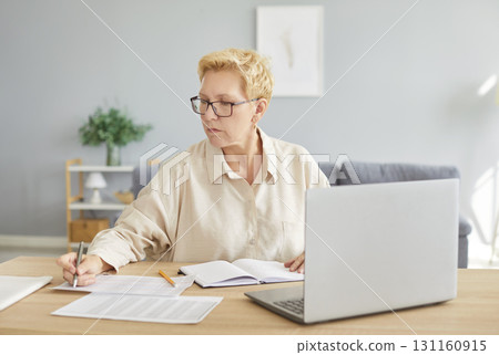 Senior accountant woman sitting on workplace at the desk with laptop working with charts 131160915