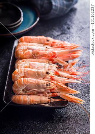 Scampi langoustine on plate on black table. Scampi langoustine on plate on black table. 131161227