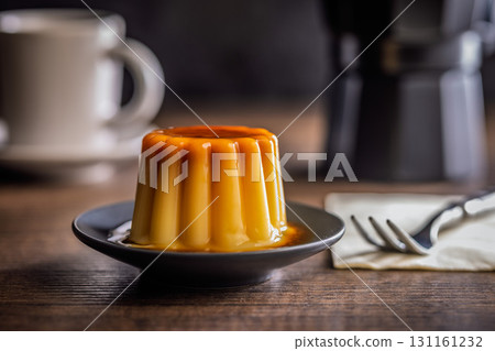 Vanilla pudding with caramel sauce on plate on wooden table. Vanilla pudding with caramel sauce on plate on wooden table. 131161232