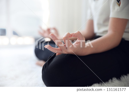 Close up image of woman's hands who was sitting cross-legged on the floor of the room at home To meditate to make the mind calm and relaxed. The room is bright with natural light. 131161577