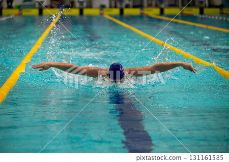 Front view swimmer performing butterfly stroke at swimming race Front view swimmer performing butterfly stroke at swimming race 131161585