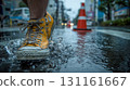 Alone, yellow shoes splashing water on a city sidewalk on a rainy day 131161667