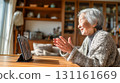 An elderly woman in her living room at home having an online call on a tablet during the day 131161669