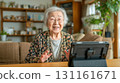 An elderly woman operates a tablet in the living room at home during the day 131161671