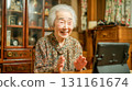 An elderly woman making an online call with a tablet in the living room during the day 131161674