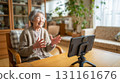 An elderly woman in her living room, having an online call during the day 131161676