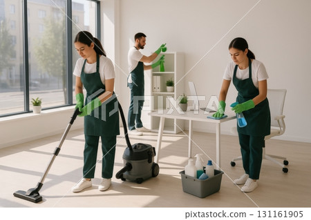 Cleaning professionals working together in a modern office space during daylight hours, ensuring a tidy and organized environment 131161905