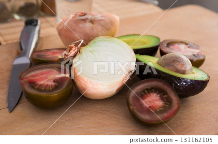 vegetables black tomatoes, avocado and onions on wooden board vegetables black tomatoes, avocado and onions on wooden board 131162105