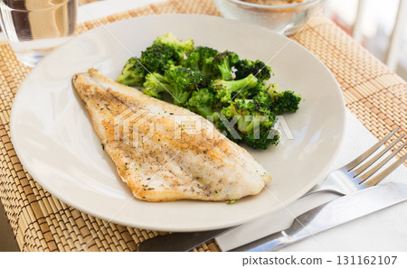 fried fillet of sea bass with garnish of broccoli on black warm stone plate fried fillet of sea bass with garnish of broccoli on black warm stone plate 131162107