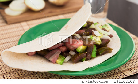 salad of black tomatoes, avocado and onions in Italian tortilla on green plate salad of black tomatoes, avocado and onions in Italian tortilla on green plate 131162108