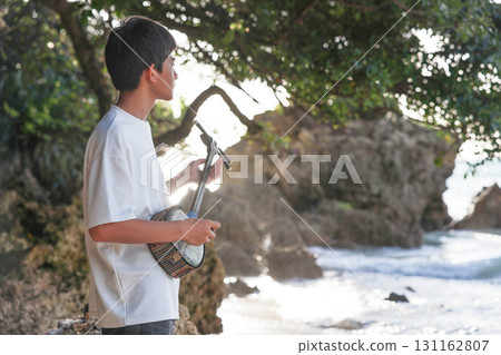 A boy playing the sanshin on the beach 131162807
