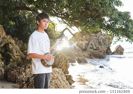 A boy playing the sanshin on the beach 131162809