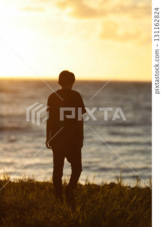 Boy standing in the sunset Boy standing in the sunset 131162824