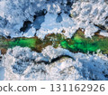Aerial view of bright green river flowing through snowy forest 131162926