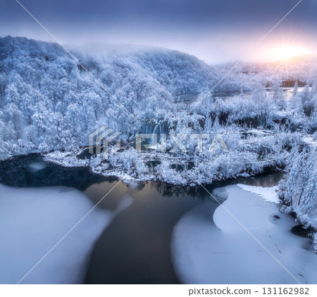 Aerial view of frozen lakes, waterfalls and snowy forest. Winter 131162982