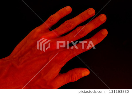 Red illuminated hand on black background Red illuminated hand on black background 131163880