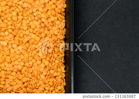 Red Lentil Grains in Black Plate on Black Stone Background Surface with Free Space Splitted in Half 131163887