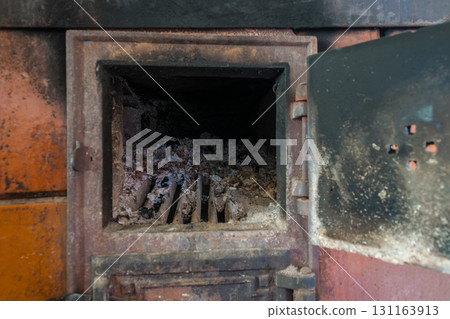 Rural Stove with Open Door. Lot of Ashes and Charcoal Visible Inside the Stove 131163913