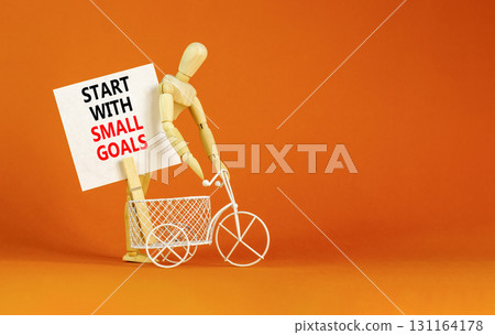 Start with small goals symbol. Concept words phrase Start with small goals on beautiful white paper on clothespin. Beautiful orange background. Business Start with small goals concept. Copy space. 131164178