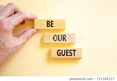 Be our guest symbol. Concept words Be our guest on beautiful wooden block. Businessman's hand. Beautiful white background. Business and be our guest concept. Copy space. 131164217